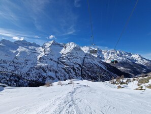 Eine verschneite Berglandschaft mit einer Seilbahn und blauem Himmel.