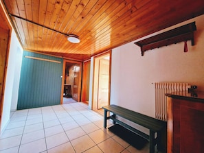A hallway with wooden ceiling and tiled floor, leading to a room with a bench and a radiator. - Faderhorn 8 Appartement/Fewo Appartement/Fewo by Interhome (Saas-Almagell)