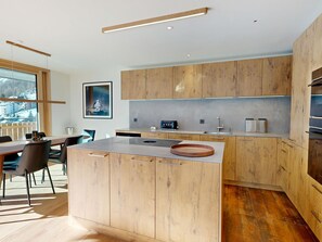 A modern kitchen with wooden cabinets, a central island, and a dining area with chairs. - Alphubel Peak & Unlimited Appartement/Fewo Peak 08 by Interhome (Saas-Fee)