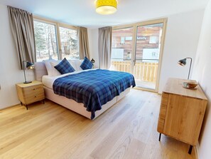 A bedroom with a bed, bedside tables, a wooden dresser, and a balcony with a view. - Alphubel Peak & Unlimited Appartement/Fewo Peak 08 by Interhome (Saas-Fee)