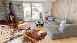 Ein modernes Wohnzimmer mit Steinwand, Kamin, Sofa und großem Fenster.