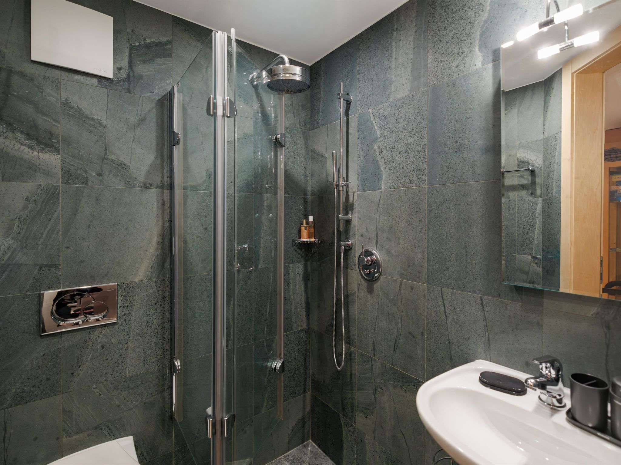 Une salle de bain moderne avec une douche à parois de verre, un lavabo blanc et un grand miroir.