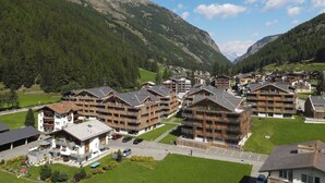 Et fjeldresort med bindingsværkshuse, en parkeringsplads og udsigt til de omkringliggende bjerge.
