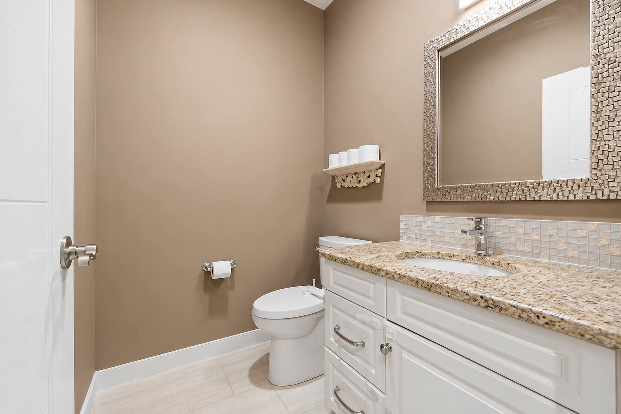A bathroom with a toilet, sink, and mirror.