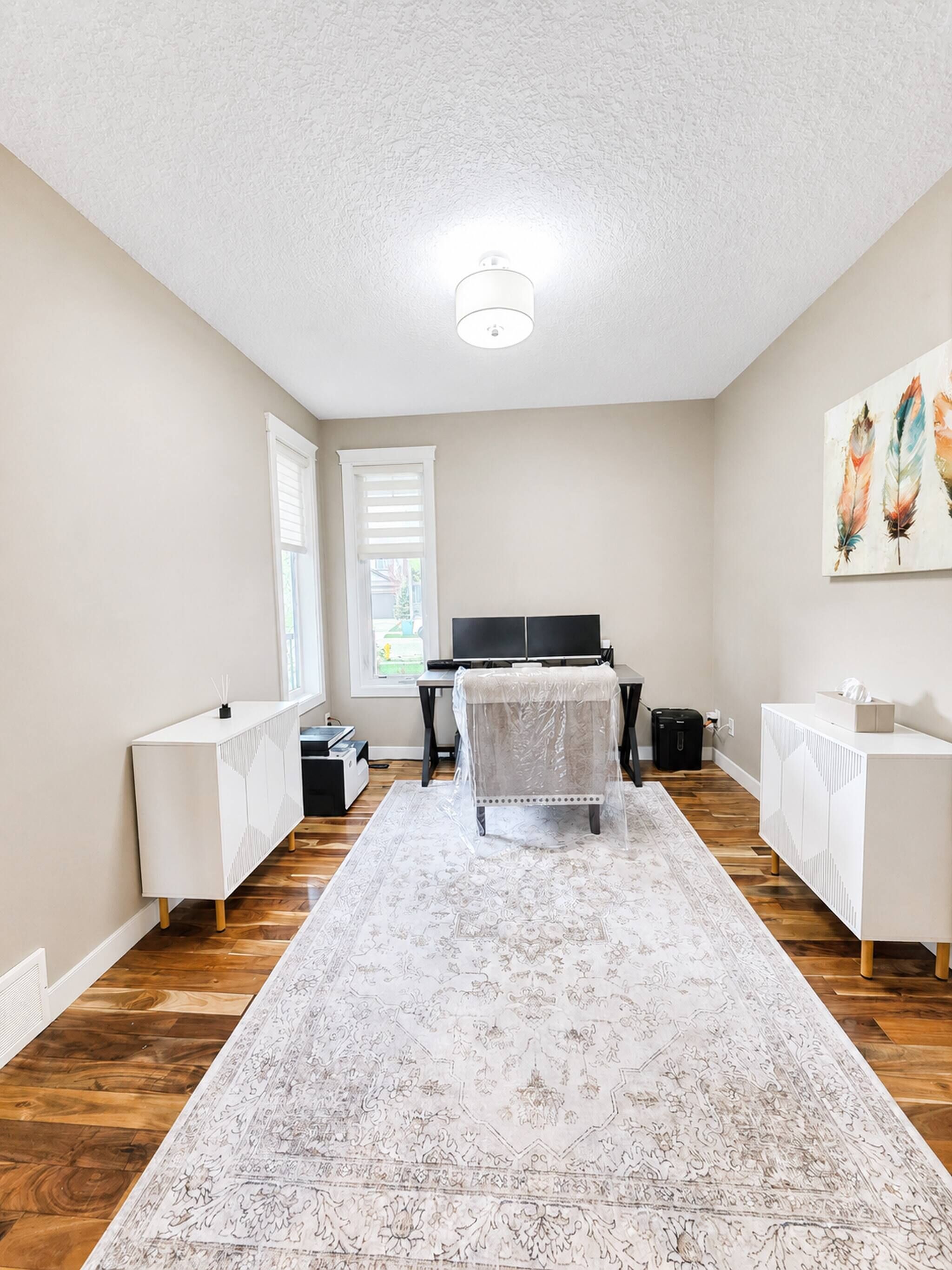Une pièce comprenant un lit, un bureau, une chaise, une armoire blanche et un tableau accroché au mur.