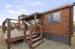 A wooden cabin with a porch and a window.