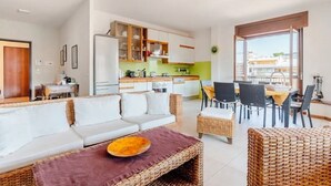 Uma sala de estar moderna com sofá, mesa de jantar e área de cozinha.
