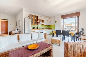 Een moderne woonkamer met een bank, eettafel en keukenhoek.
