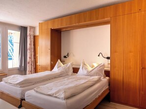 A double bed with wooden headboard, a bedside table, and a lamp. - Utoring Hohe Promenade 109&110 Appartement/Fewo, Dusche, WC, 4-Bettwohnung by Interhome (Arosa)