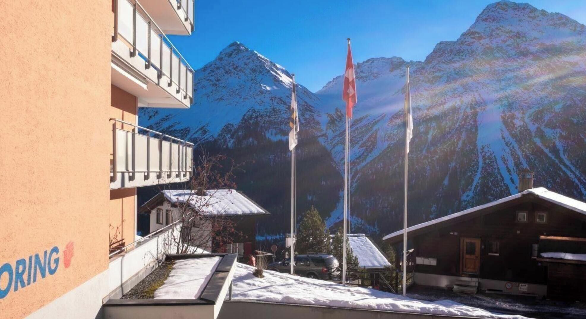 Ein Hotel mit Blick auf die Berge, einer Fahnenstange und einem Gebäude mit Balkon.