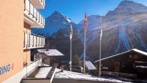 A hotel with a mountain view, a flagpole, and a building with a balcony. - Utoring Hohe Promenade 110 Appartement/Fewo, Dusche, WC, 2-Bettwohnung by Interhome (Arosa)