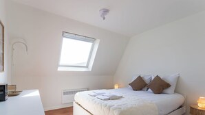 Una camera da letto con un letto, comodino, lampada, finestra e termosifone.
