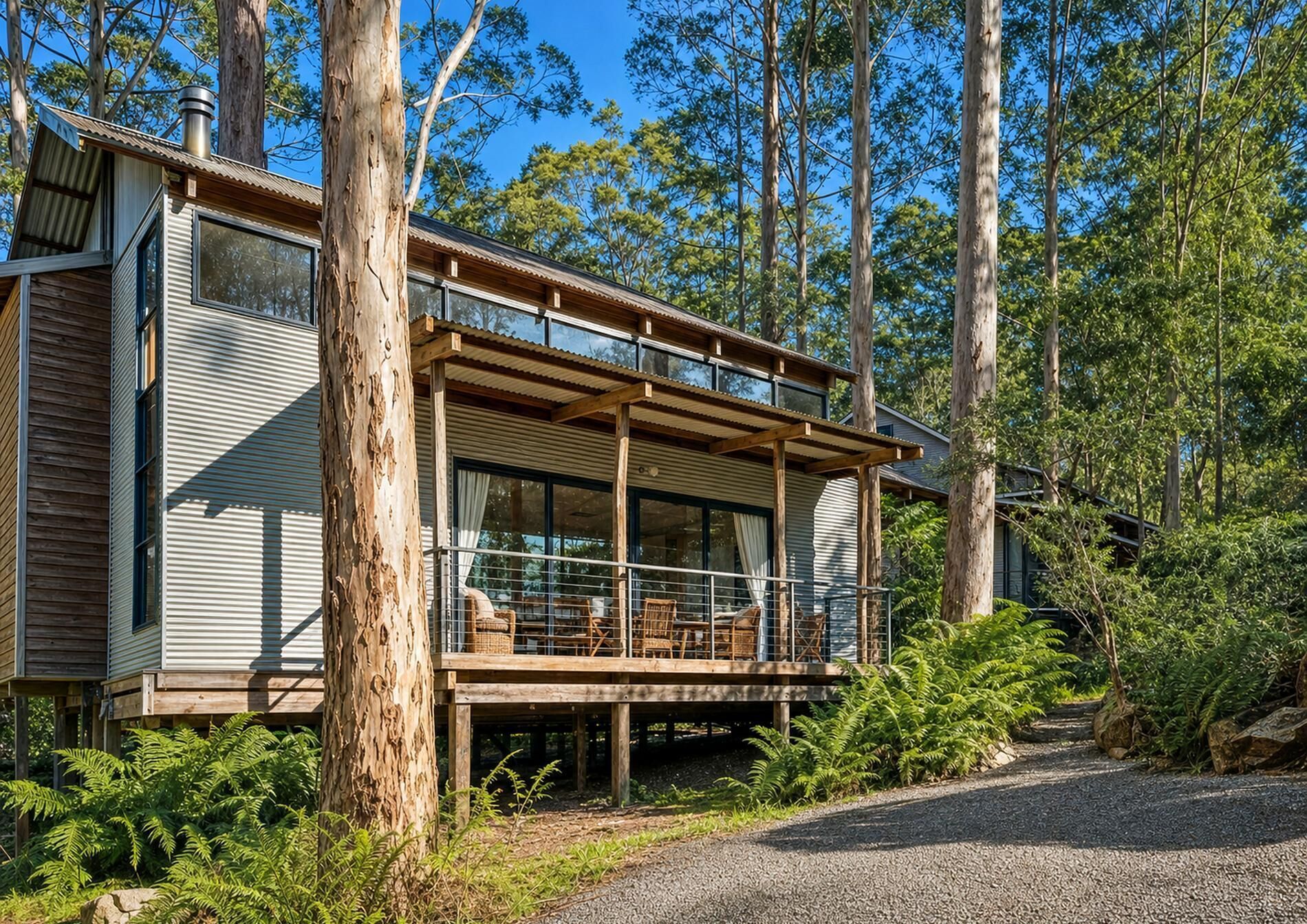 A modern wooden cabin with a balcony, surrounded by trees.
