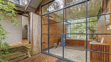 A wooden cabin with a glass door leading to a stone-tiled patio.