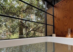 A room with a large window, a wooden cabinet, and a white shelf.