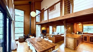 A spacious cabin with a wooden interior, a dining area, a living room with a fireplace, and a kitchen area. - Inglenook: Cosy forest escape, 5min to Denmark (Denmark)