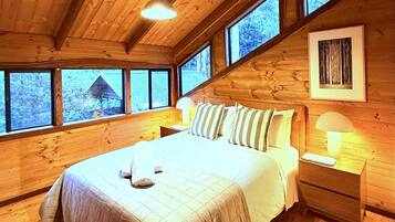 Une chambre dans une cabane en bois, avec un lit, des tables de chevet et une fenêtre donnant sur le paysage.
