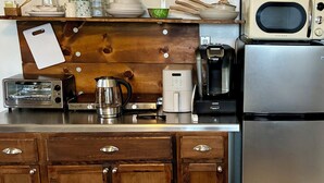 Una cocina con armarios de madera, un tostador, un hervidor, una cafetera, un microondas y un refrigerador.