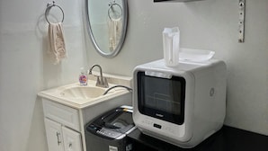 Un baño pequeño con lavamanos, espejo, toallero y lavadora.