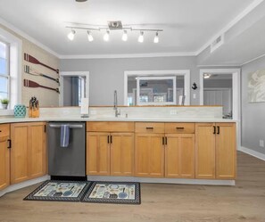 A modern kitchen with wooden cabinets, a stainless steel dishwasher, and a large island. - Classic Dreams | 4BR Marsh Oasis Near the Beach (North Myrtle Beach)