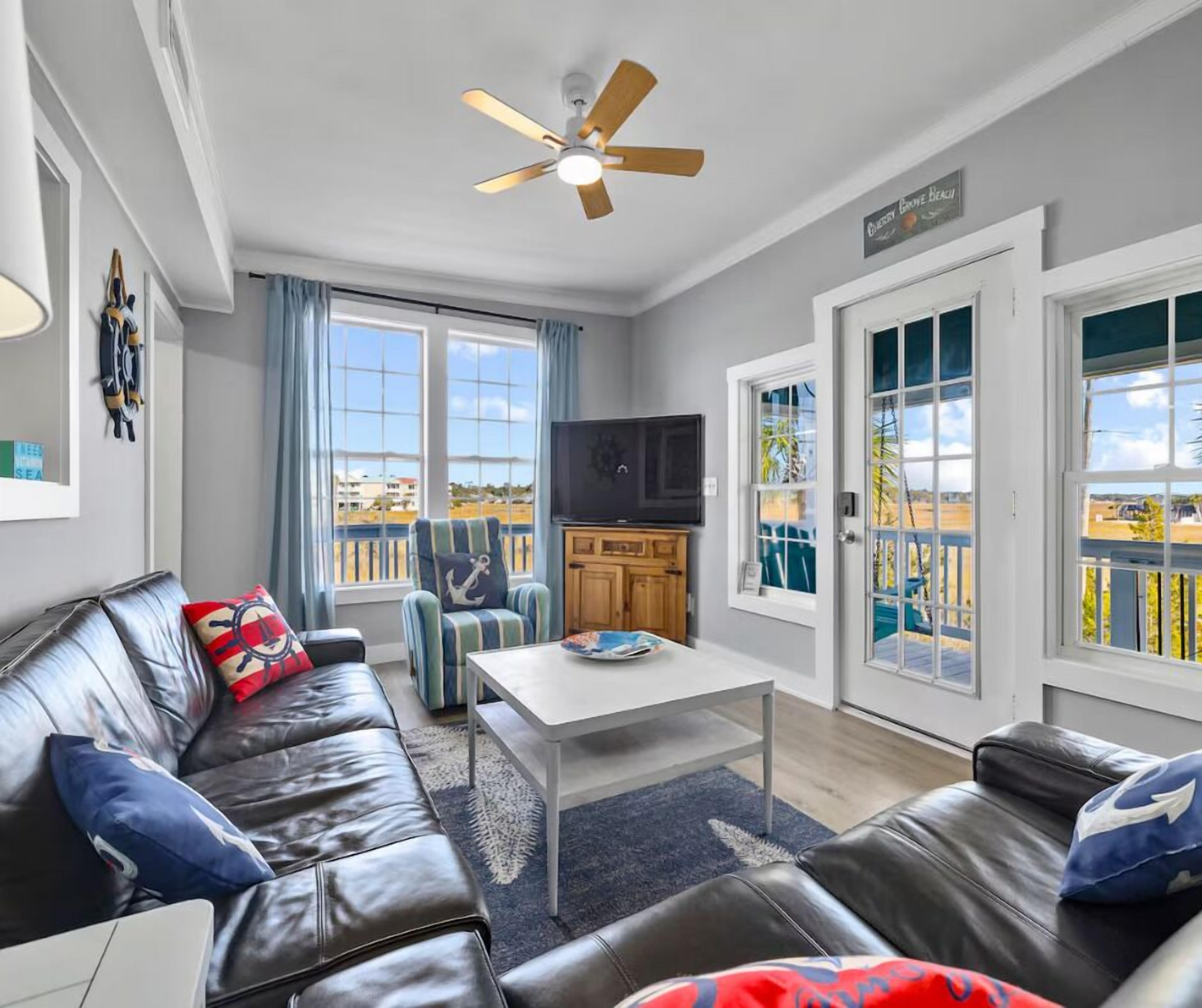 A living room with a sofa, a coffee table, a TV, and a ceiling fan.