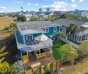 A two-story house with a balcony, a fenced yard, and a view of the surrounding neighborhood. - Classic Dreams | 4BR Marsh Oasis Near the Beach (North Myrtle Beach)