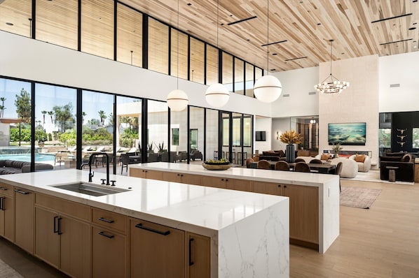 Cocina amplia con una isla grande, techo de madera y ventanas grandes.