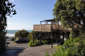 A coastal property with a wooden deck, a garage, and a view of the ocean. - Entire home in Waimārama, sea views, 2 minute walk to the beach. (Waimārama)