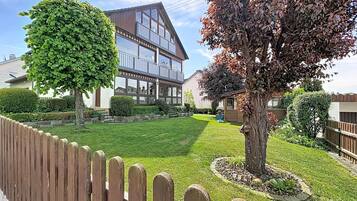 Ein modernes, zweistöckiges Haus mit großem Panoramafenster, einem gepflegten Rasen und einem Holzzaun.