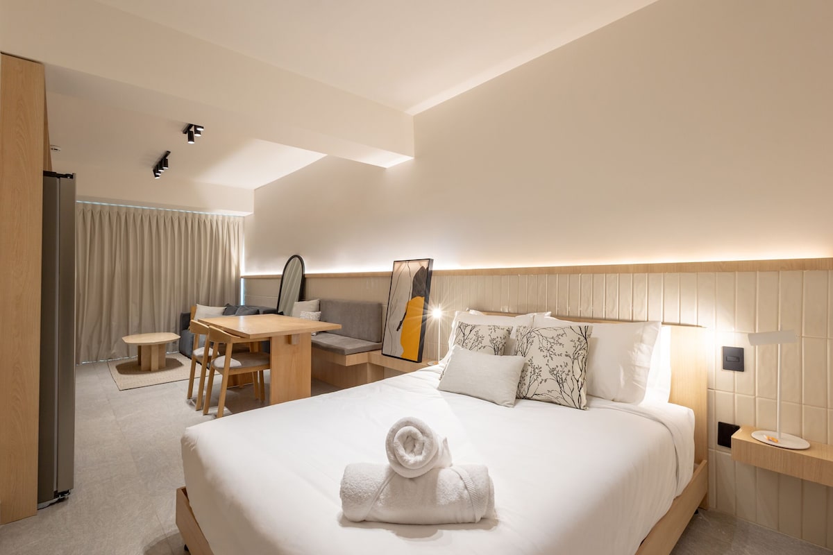Habitació d'hotel amb un llit gran, una taula de treball, una cadira i un sofà.