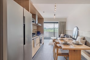 A modern kitchen with built-in appliances, a dining area with a table set for two, and a large window offering a view of the outdoors. - Myla Girasol  (Ciudad de México)