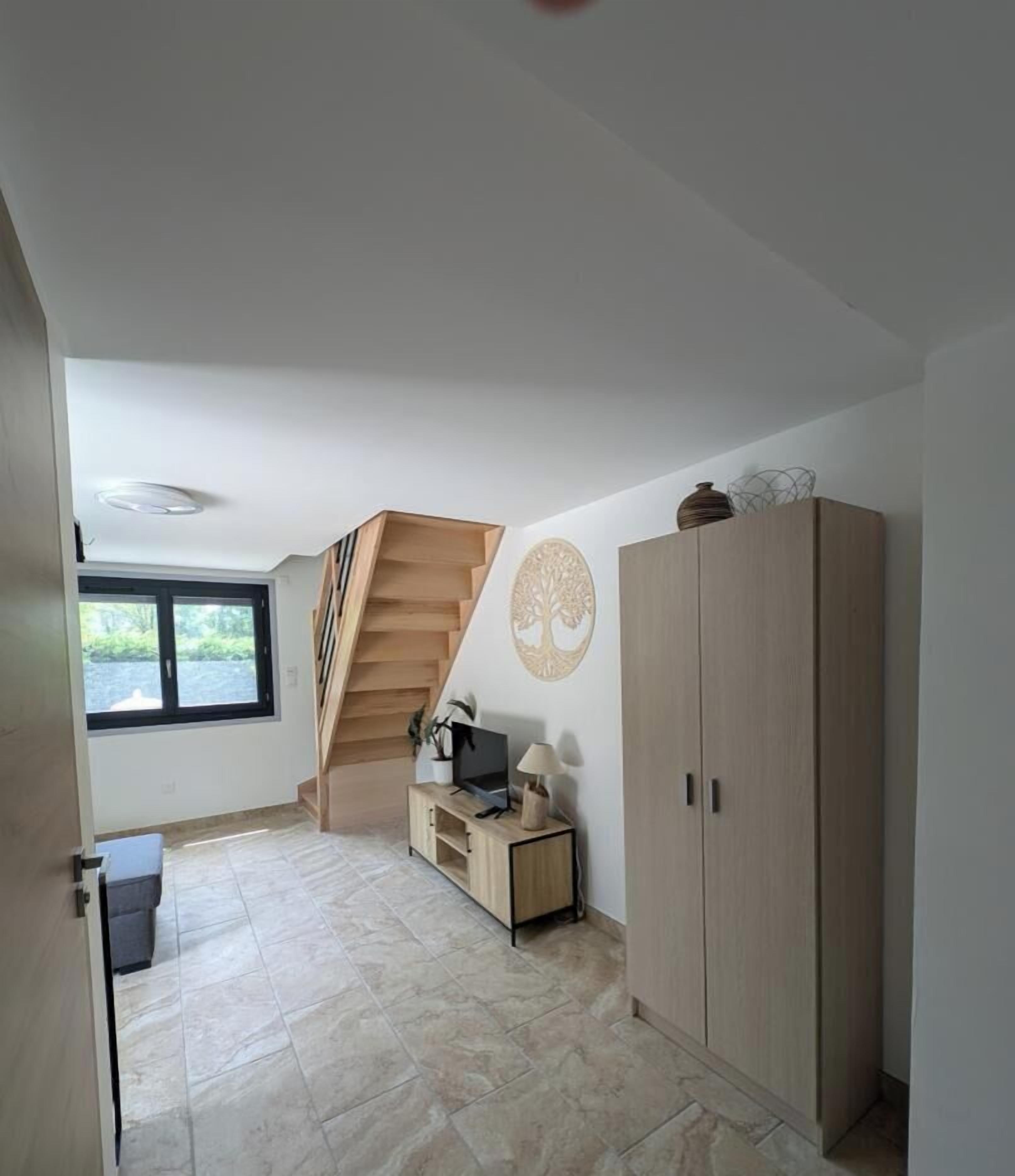 Ein Zimmer mit Treppe, Fernseher, Schrank und Fenster.
