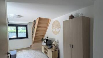 Ein Zimmer mit Treppe, Fernseher, Schrank und Fenster.