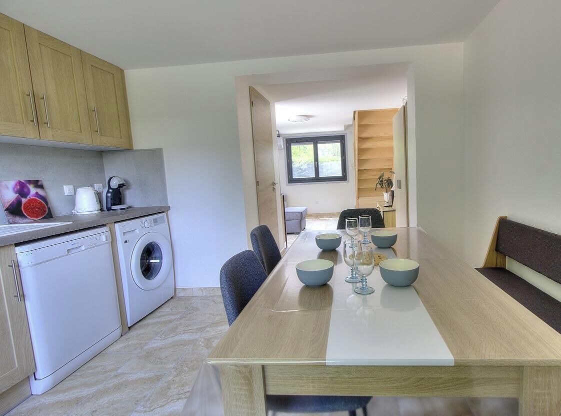 A modern kitchen with a dining area, including a washing machine, a sink, and a table set for dining.