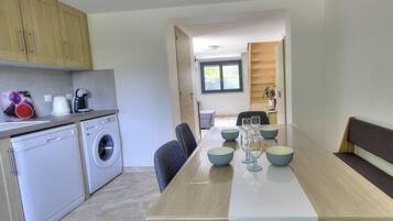 A modern kitchen with a dining area, including a washing machine, a sink, and a table set for dining.