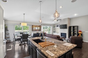 A modern kitchen with a granite countertop, a built-in oven, and a dining area with a table and chairs.