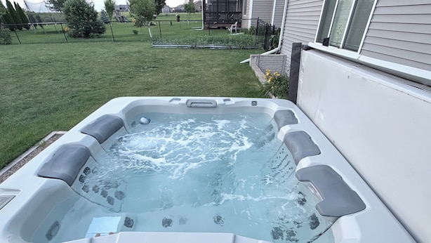 A hot tub with a clear view of the surrounding yard and house.