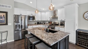 A modern kitchen with stainless steel appliances, a granite countertop, and pendant lighting.
