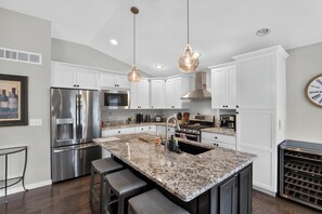 A modern kitchen with stainless steel appliances, a granite countertop, and pendant lighting.