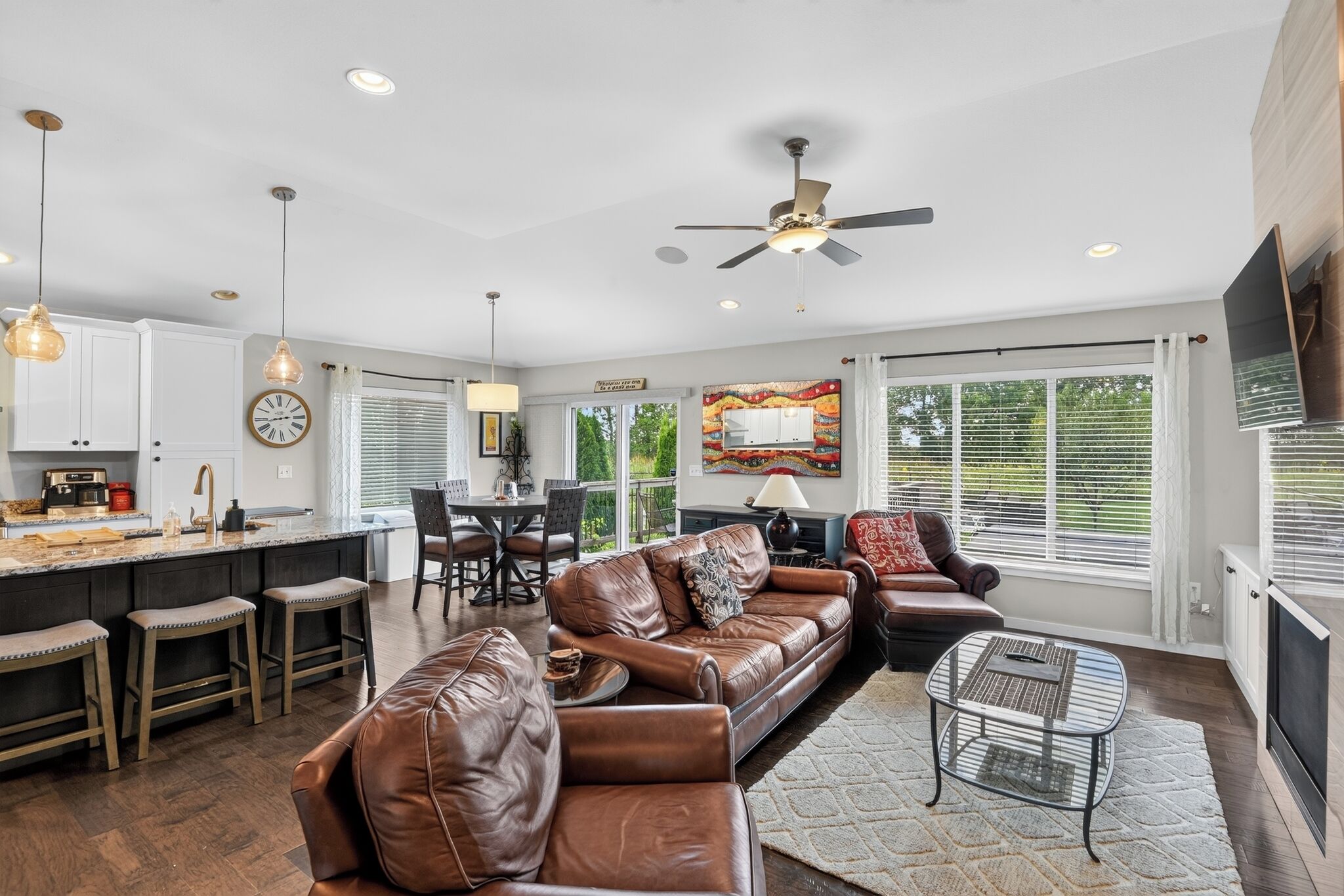 A modern kitchen with a dining area, leather sofas, and a fireplace.