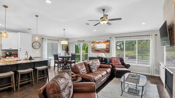 A modern kitchen with a dining area, leather sofas, and a fireplace.