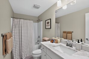 A modern bathroom with a shower curtain, a toilet, a sink with a mirror, and a towel rack.