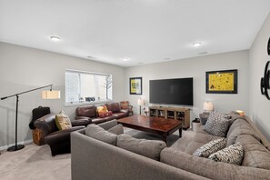 Ein modernes Wohnzimmer mit einem Ecksofa, einem Couchtisch, einem Fernseher und einer Stehlampe.