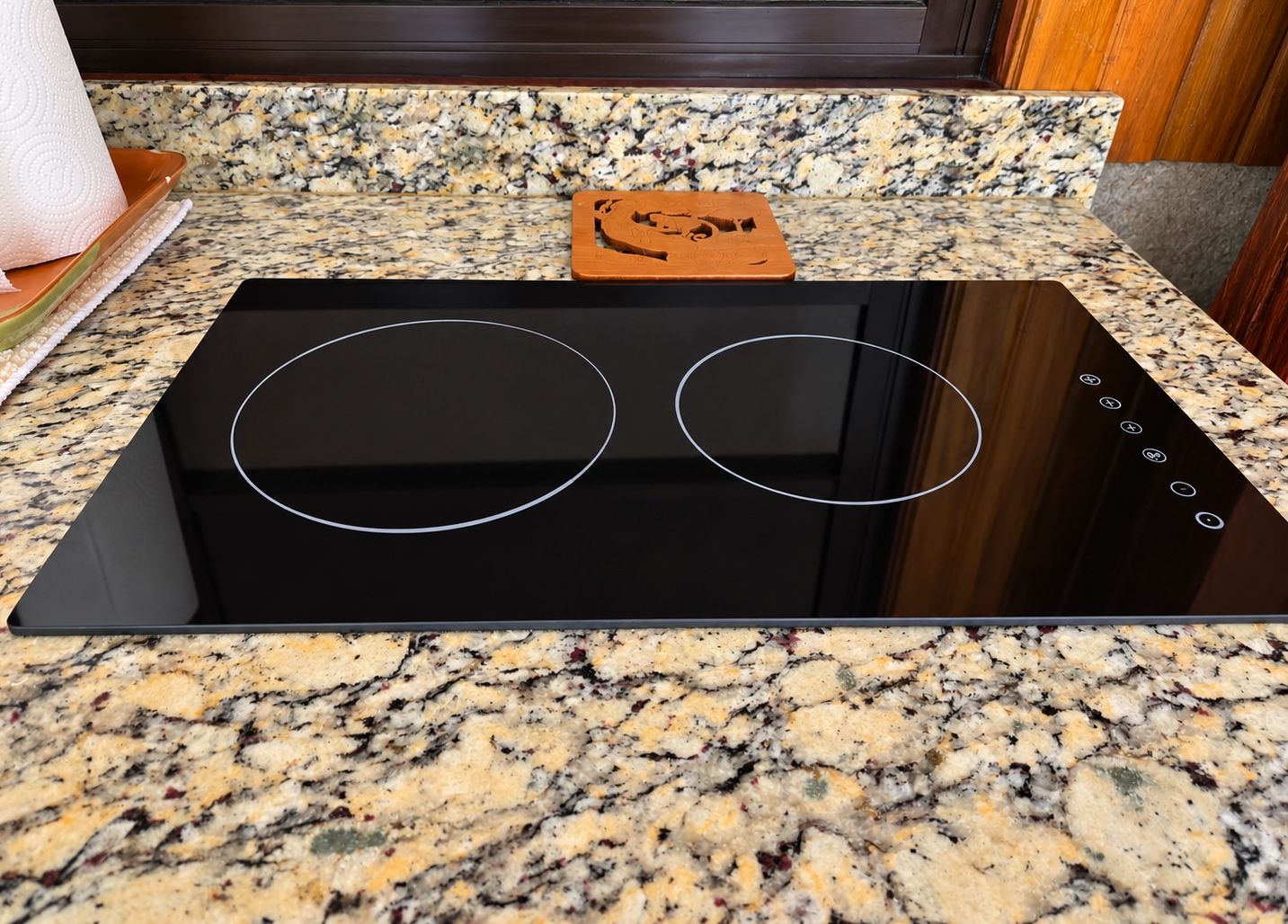 Una cocina con tope de inducción negro y encimera de granito.