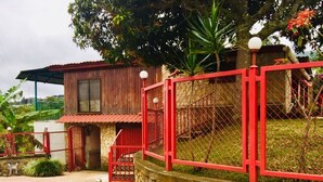 A rustic building with a stone wall, a red fence, and a paved walkway. - Escazu Studio (San Antonio)