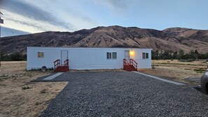 A single-story mobile home with a gravel driveway and a mountain backdrop. - 2-bedroom mobile home in welcoming Naches country area (Naches)