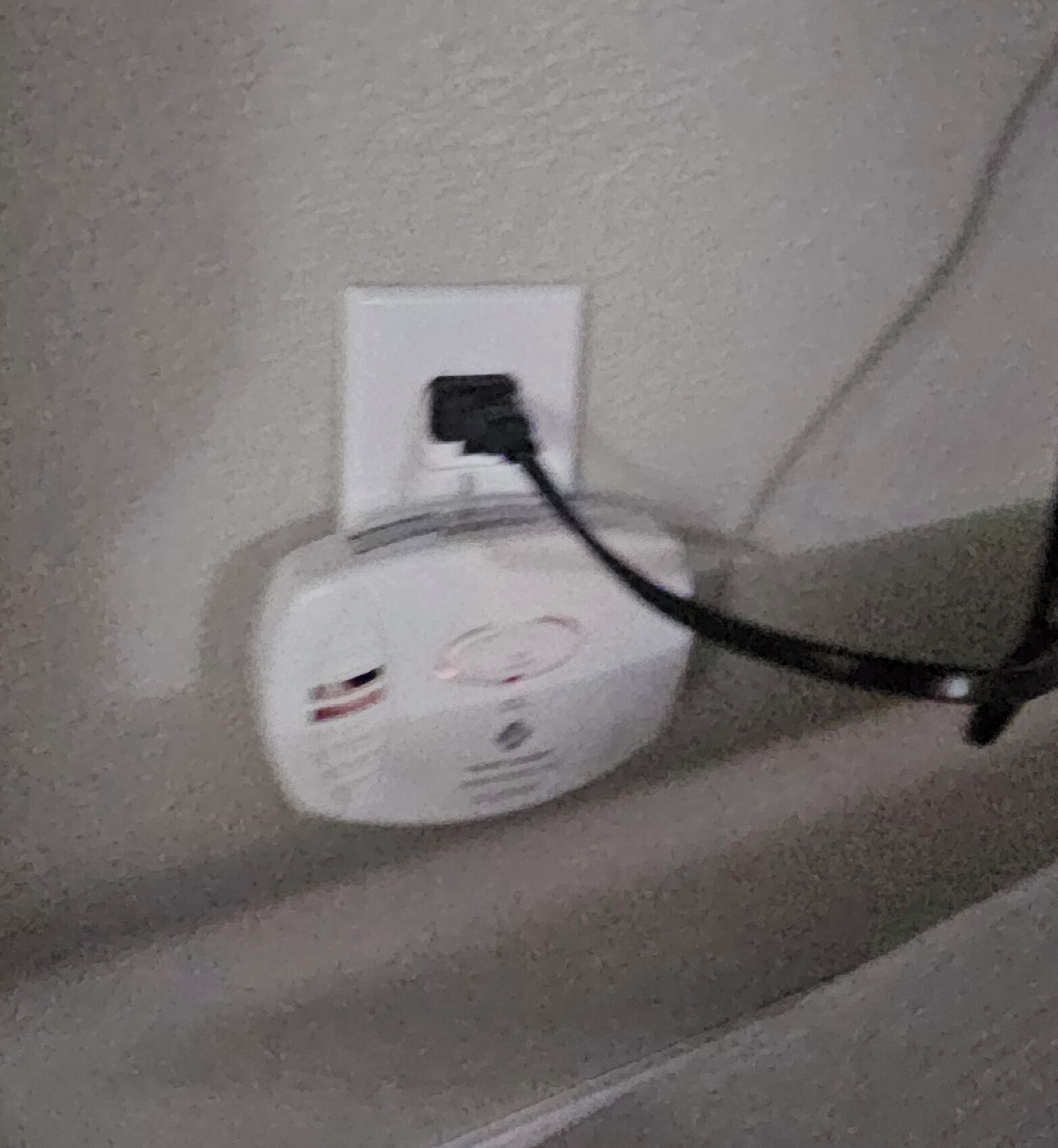 Um dispositivo elétrico branco fixado na parede com um cabo preto conectado.