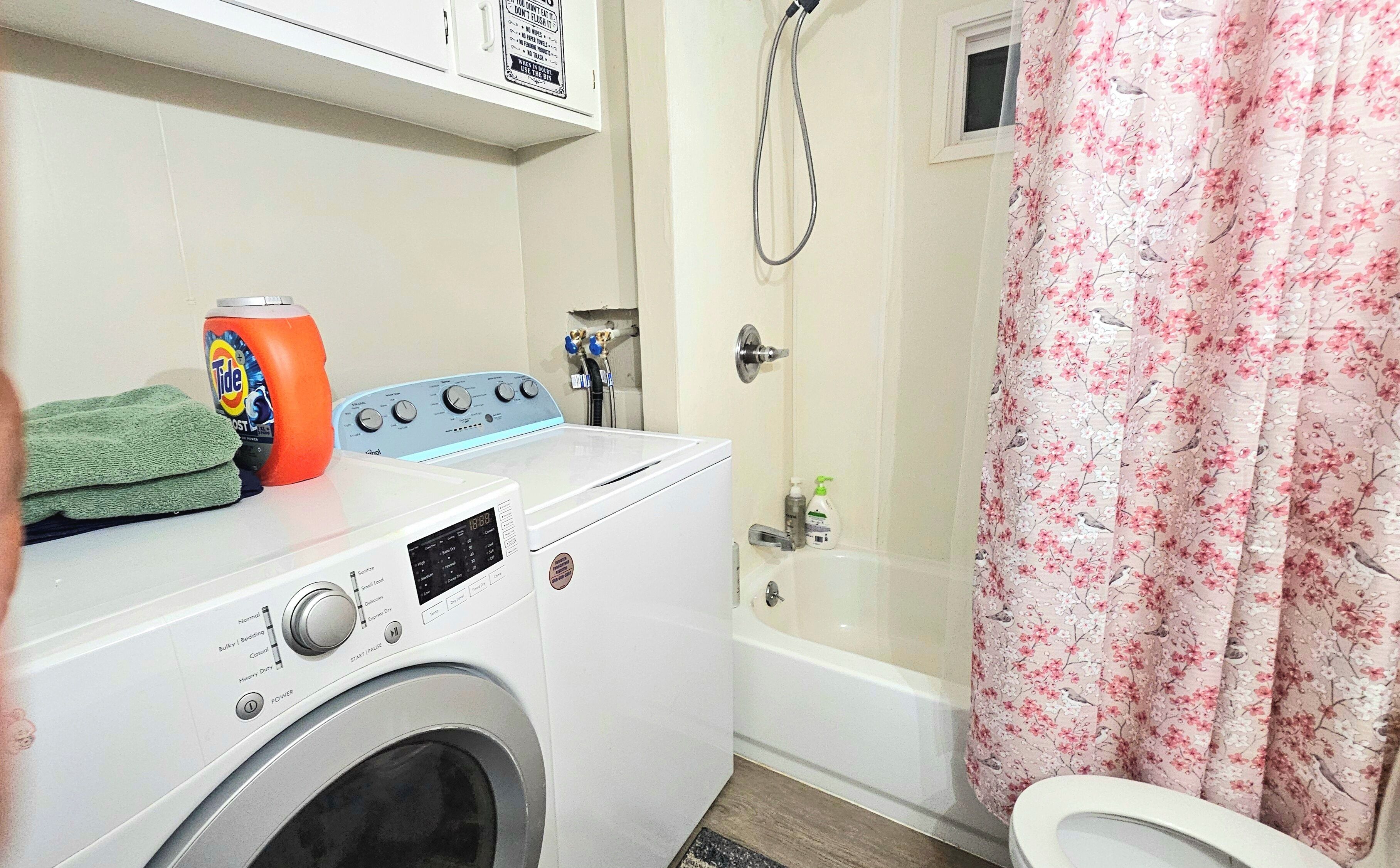 A laundry area with a washing machine, a dryer, and a shower curtain.