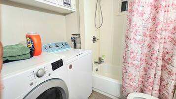 A laundry area with a washing machine, a dryer, and a shower curtain.