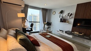 Una habitación de hotel moderna con una cama grande, un escritorio, un televisor y vistas a la ciudad.